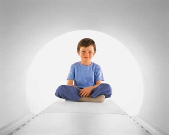 a little boy sitting inside a wide bore MRI machine